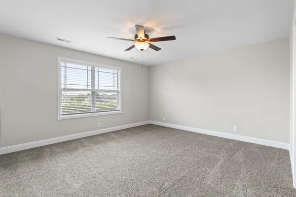 an empty room with windows and fan