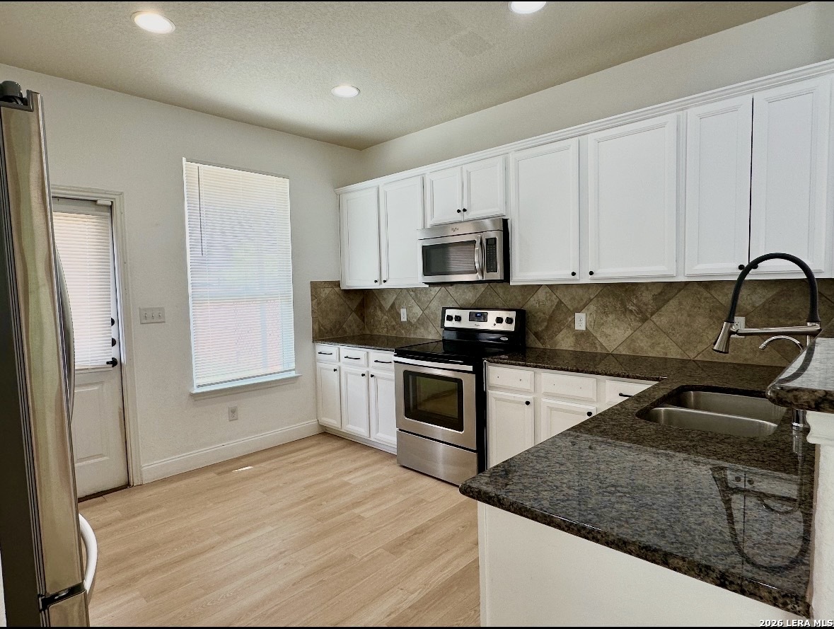 443 Harvest Point Schertz, TX 78154 - Photo 6 of 13 a kitchen with granite countertop a sink cabinets and stainless steel appliances