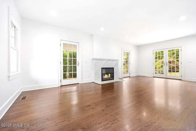 an empty room with wooden floor fireplace and windows