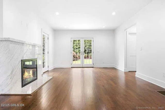 a view of an empty room with a window and wooden floor