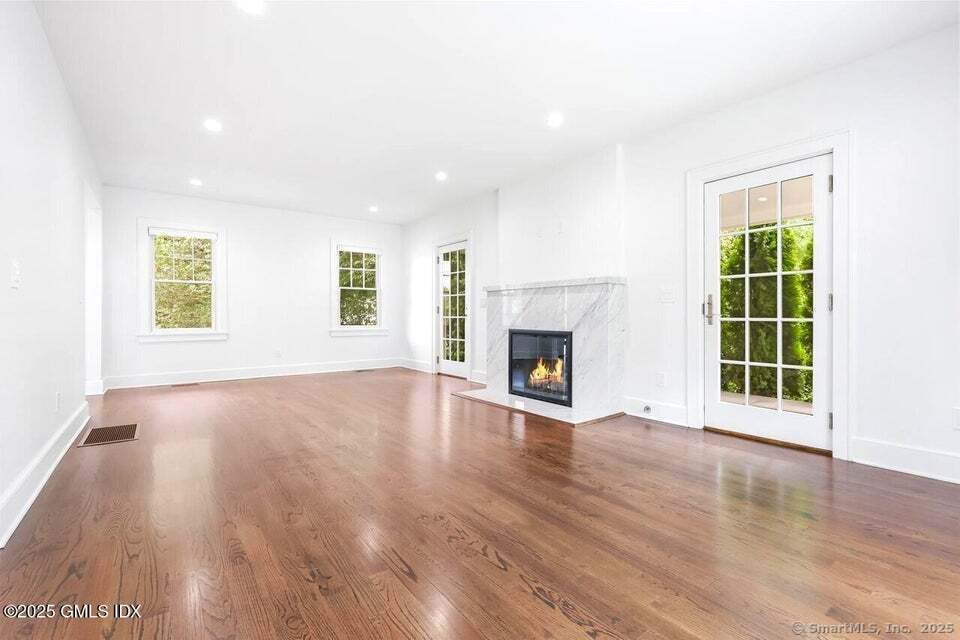 2 Sound View Terrace Greenwich, CT 06830 - Photo 15 of 39 an empty room with windows a fireplace and wooden floor