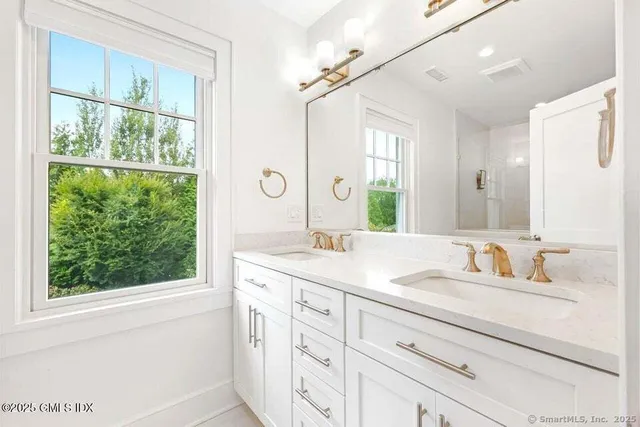 a bathroom with a granite countertop sink mirror and a window