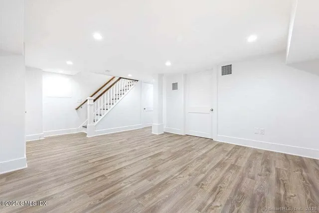 a view of an empty room with wooden floor and stairs