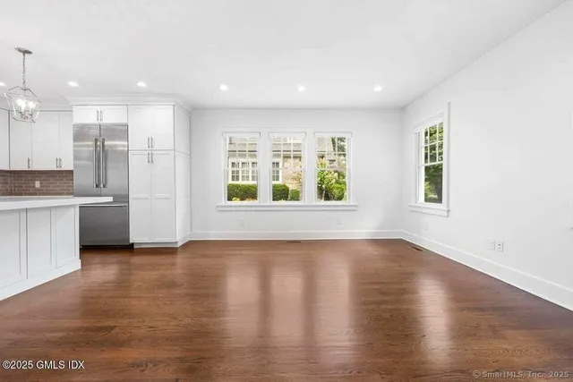 a view of an empty room with a window and wooden floor