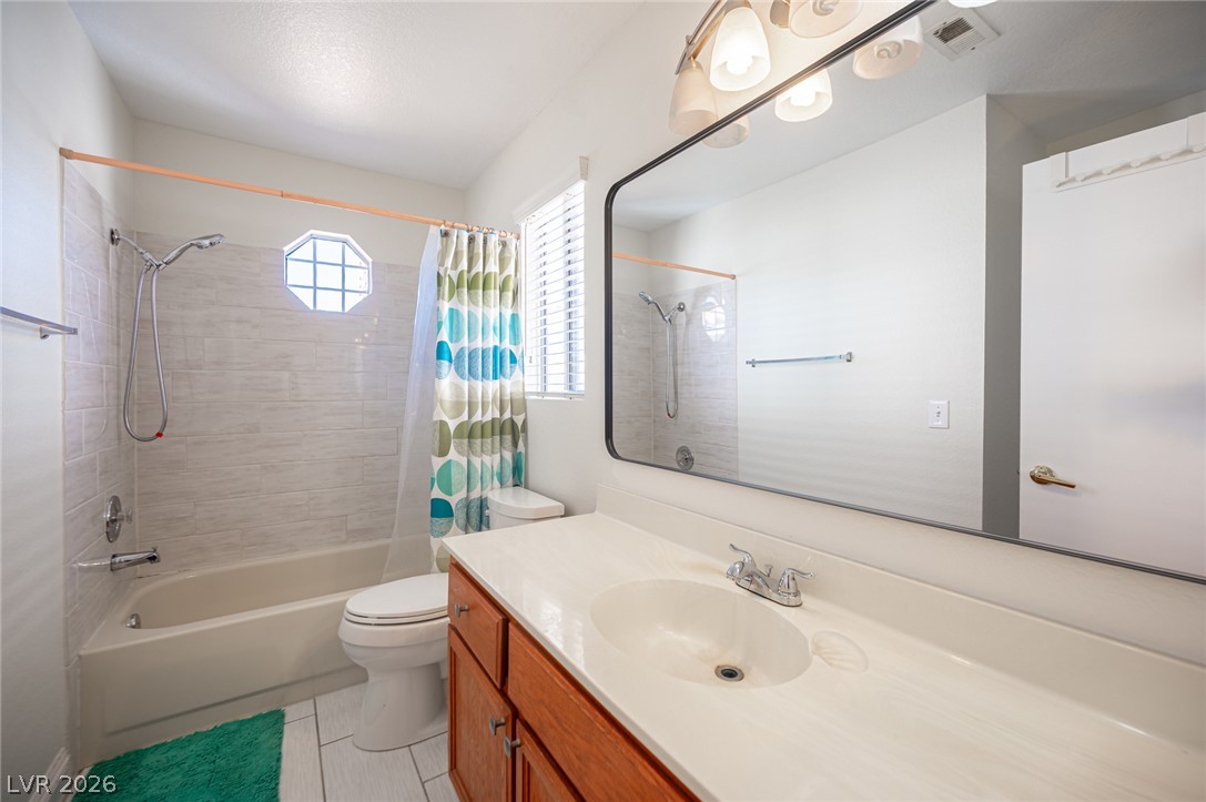 718 Rusty Spur Drive Henderson, NV 89014 - Photo 41 of 50 A pristine bathroom featuring a large mirror, practical vanity, and tiled shower area with an octagonal window.