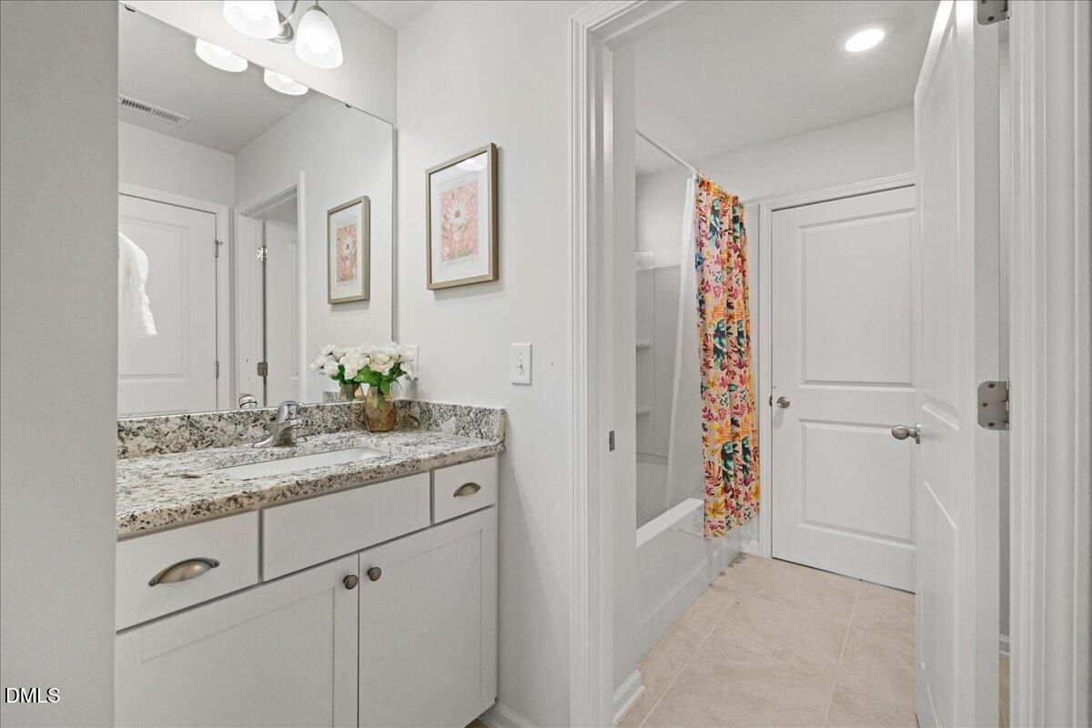 7804 Charters End Street Willow Spring, NC 27592 - Photo 33 of 43 a bathroom with a granite countertop sink a mirror and a shower