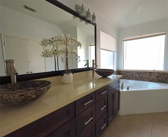 a bathroom with a granite countertop sink a large mirror and a bathtub
