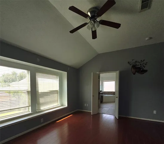 a view of empty room with wooden floor and fan