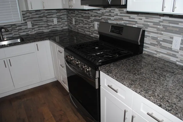 a kitchen with granite countertop white cabinets and black appliances