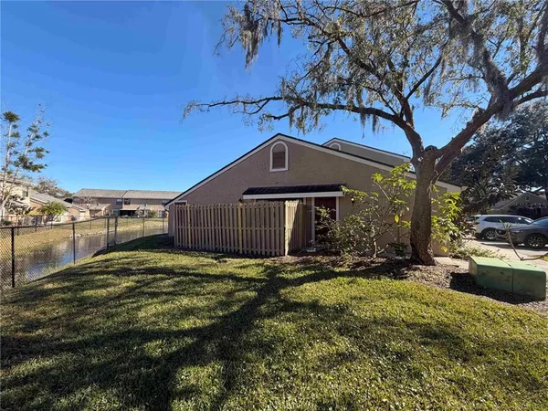 a view of a house with a yard covered with large trees