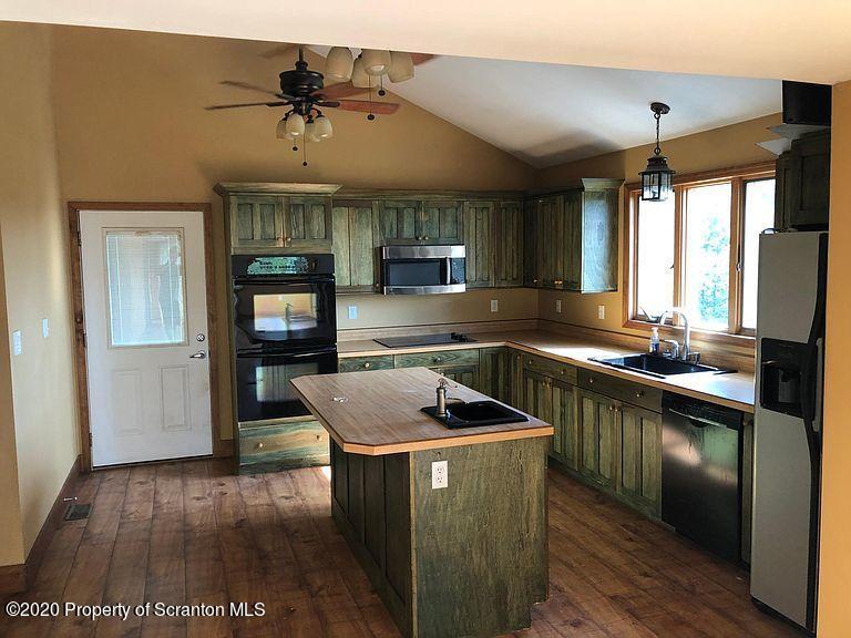 6197 Spring Hill Road Wyalusing, PA 18853 - Photo 4 of 15 a kitchen that has a sink a microwave oven a stove and white cabinets with wooden floor