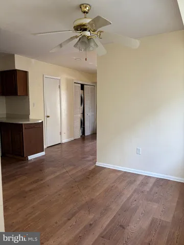 an empty room with wooden floor and ceiling fan