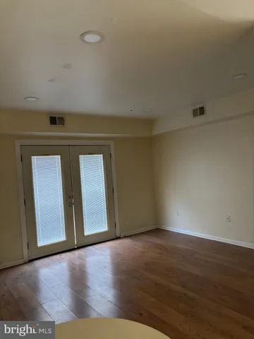 a view of an empty room with wooden floor and closet