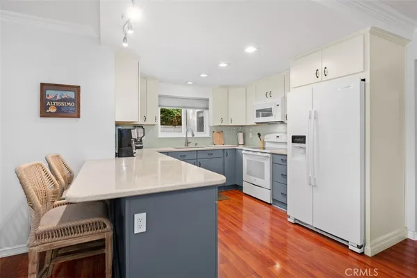 a kitchen with stainless steel appliances granite countertop a refrigerator a sink a stove a dining table and chairs with wooden floor