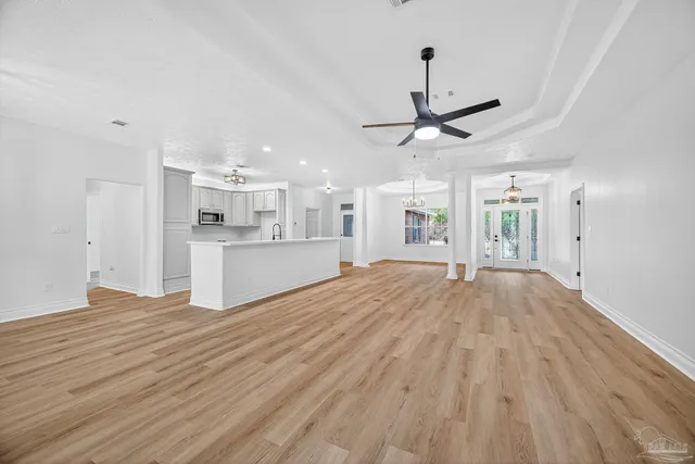 a large white kitchen with kitchen island a sink wooden floor and a refrigerator