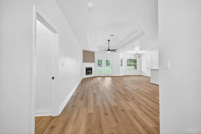 a view of a big room with wooden floor a ceiling fan and windows