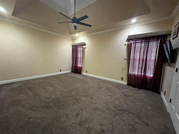 an empty room with windows and fan