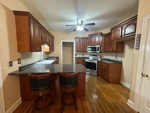 a kitchen with kitchen island granite countertop a sink stainless steel appliances and cabinets