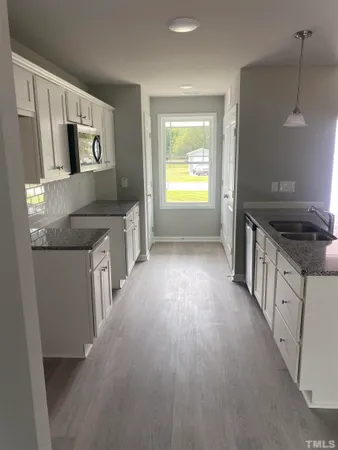 a kitchen with granite countertop a sink stove and refrigerator