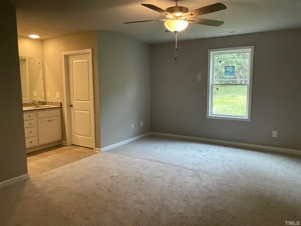 an empty room with chandelier fan and windows