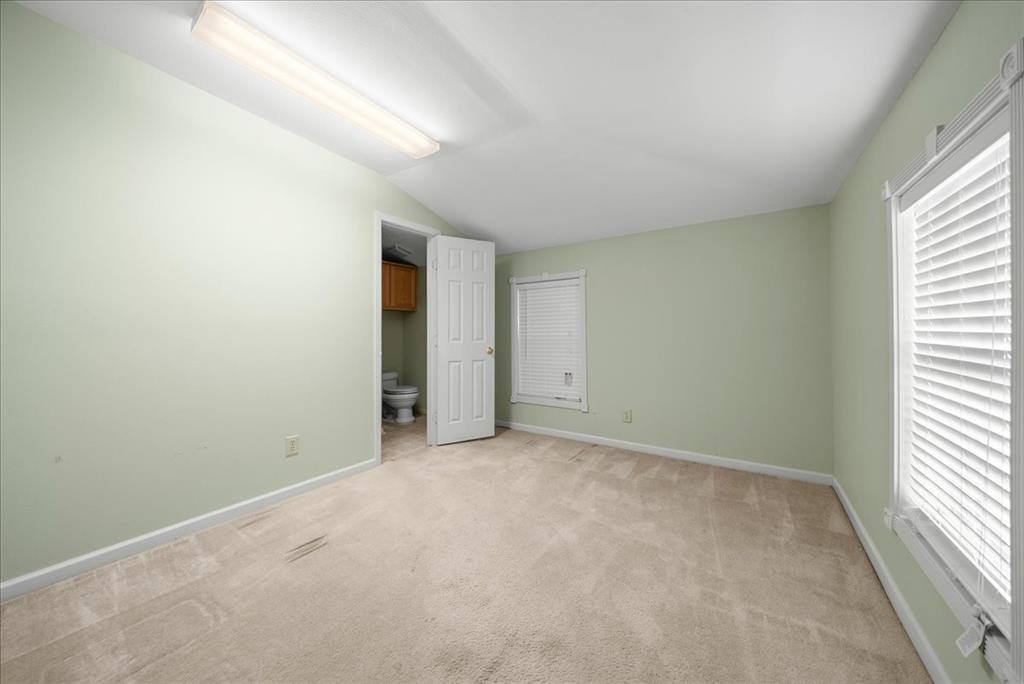 101 North 7th Street Krum, TX 76249 - Photo 13 of 26 Unfurnished bedroom featuring light colored carpet, lofted ceiling, and ensuite bathroom