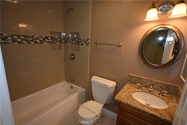 a bathroom with a granite countertop toilet sink and mirror