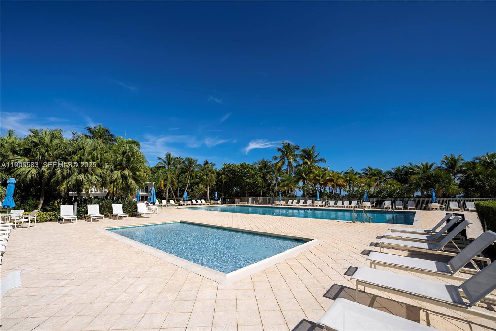 881 Ocean Drive, Unit TH15 Key Biscayne, FL 33149 - Photo 23 of 26 a view of a swimming pool that has lawn chairs with plants and palm trees