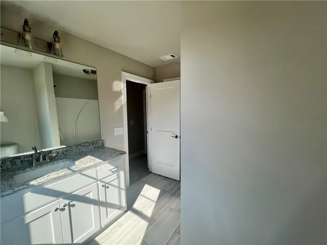 a bathroom with a granite countertop sink a toilet and a large mirror