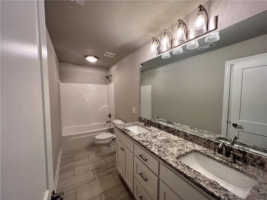 514 Adventure Trail Jefferson, GA 30549 - Photo 40 of 48 a bathroom with a granite countertop sink a toilet and a large mirror