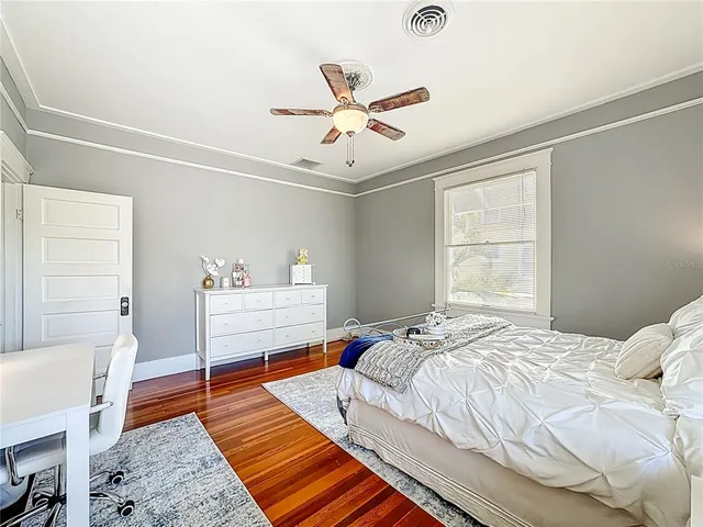a view of empty room with wooden floor and fan