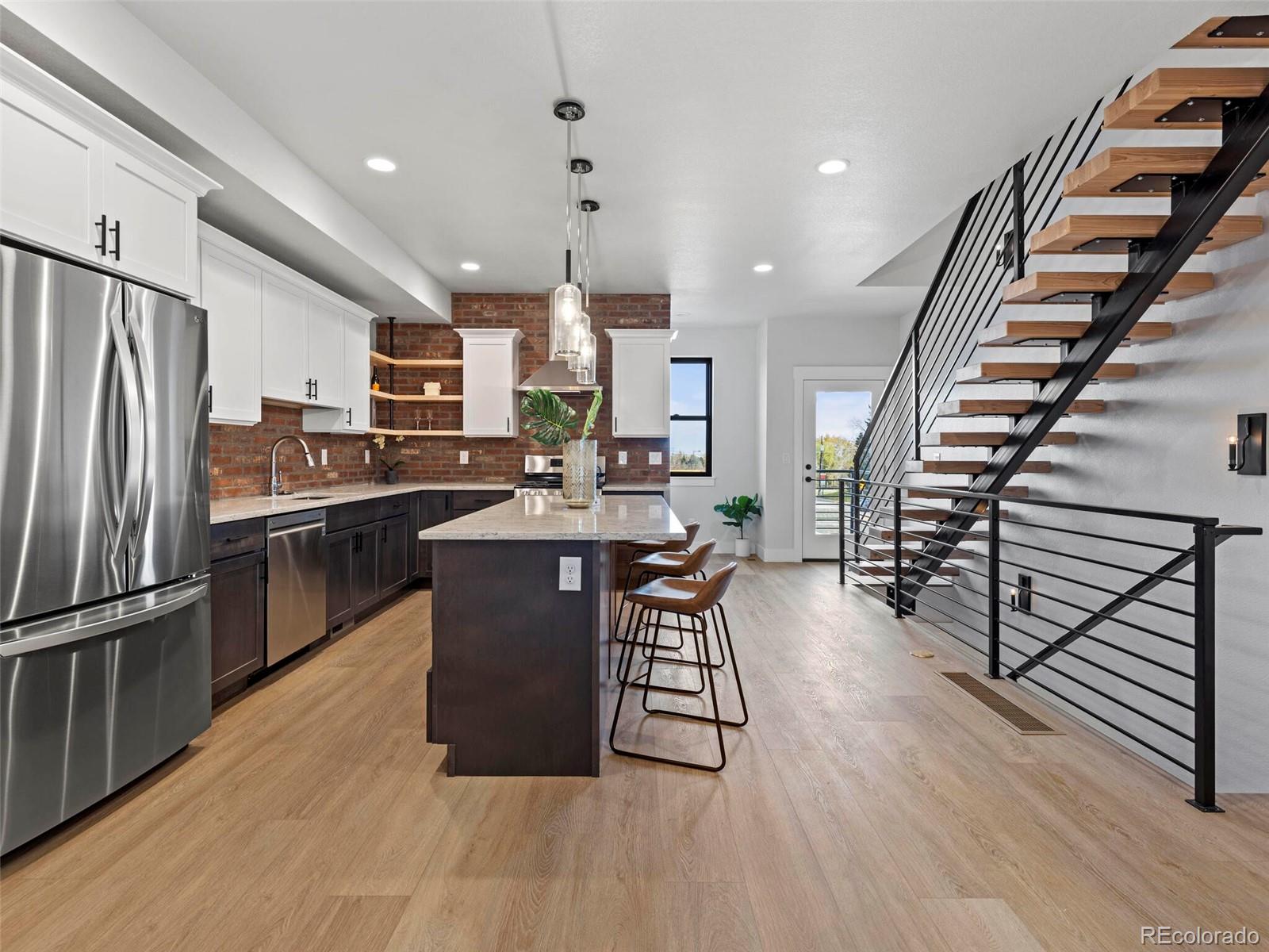 5423 South Prince Street, Unit B Littleton, CO 80120 - Photo 11 of 40 a kitchen with stainless steel appliances a refrigerator a stove a sink dishwasher and a dining table with wooden floor