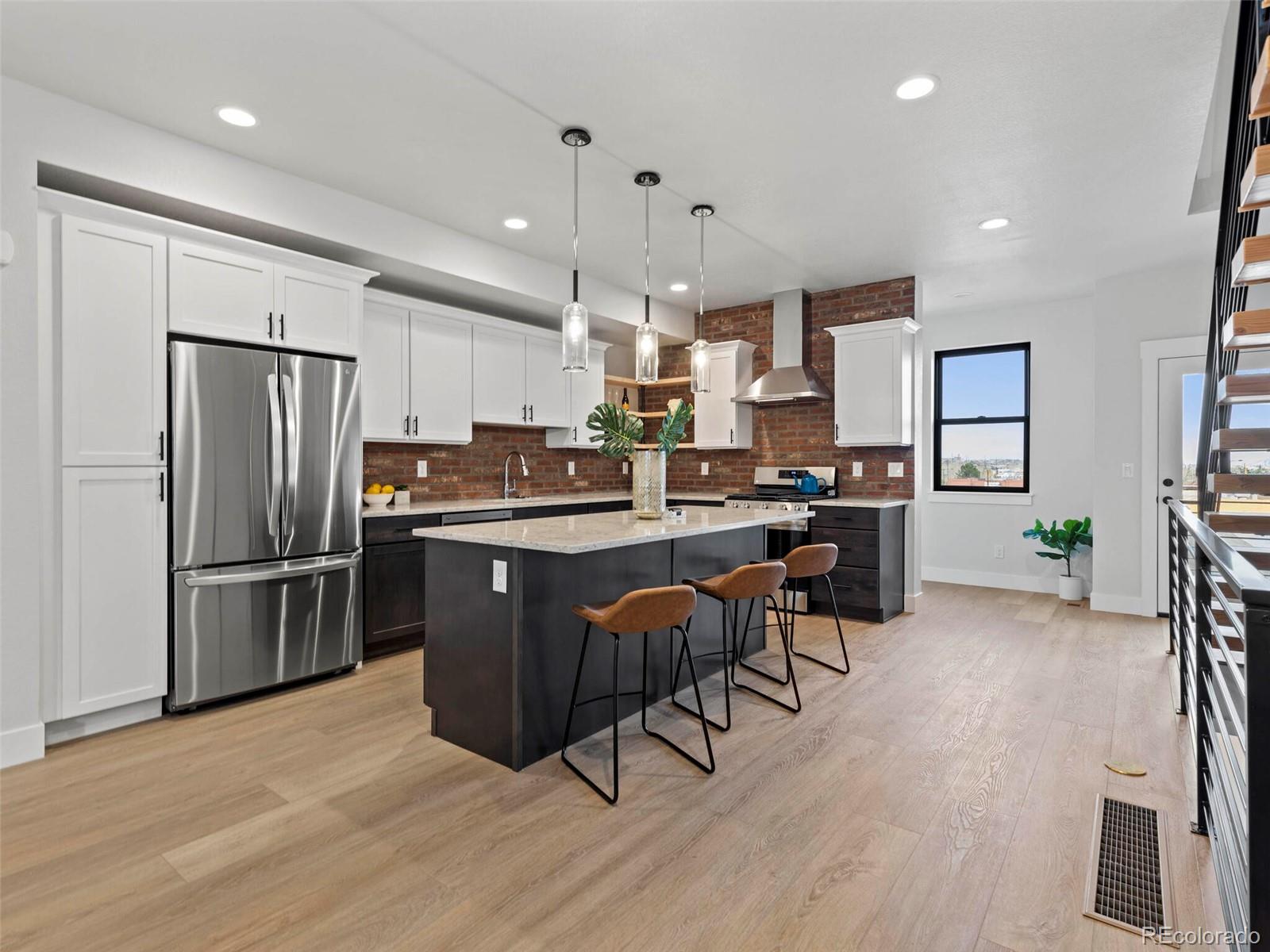 5423 South Prince Street, Unit B Littleton, CO 80120 - Photo 13 of 40 a kitchen with stainless steel appliances a refrigerator a stove a sink dishwasher and a dining table with wooden floor