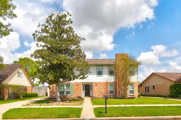 a view of a house with a big yard and large trees