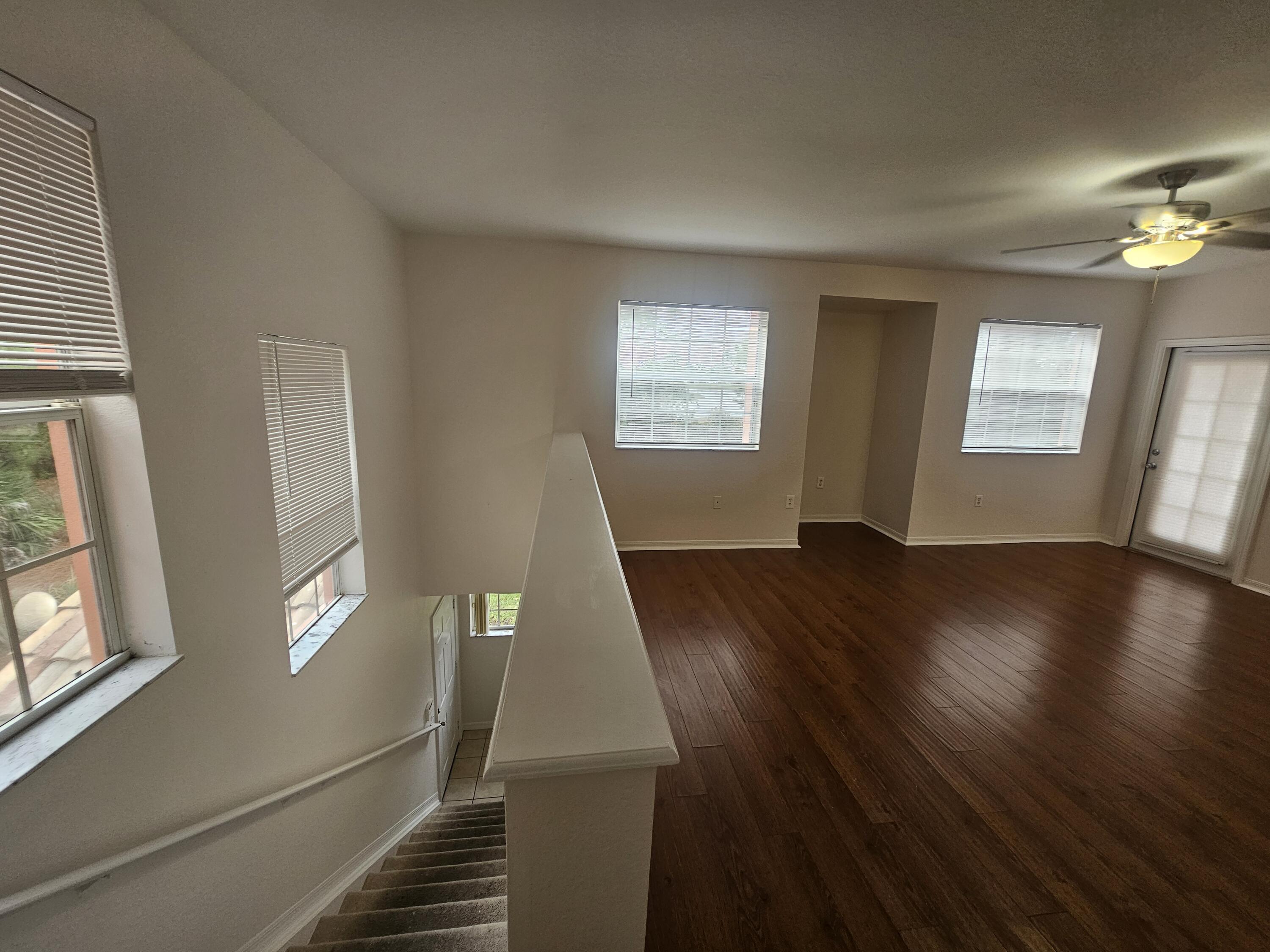 118 Southwest Peacock Boulevard, Unit 10203 Port St. Lucie, FL 34986 - Photo 2 of 10 a view of an empty room with wooden floor and a window