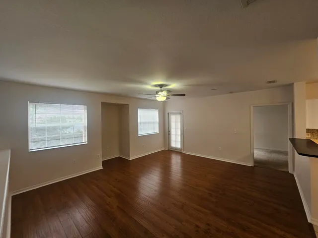 an empty room with wooden floor cabinet and windows