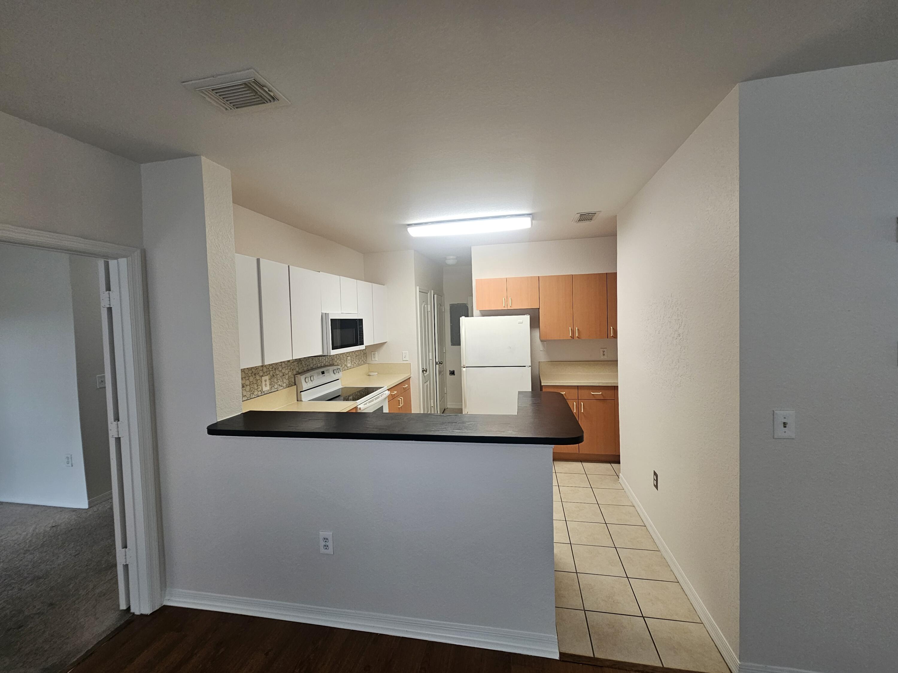 118 Southwest Peacock Boulevard, Unit 10203 Port St. Lucie, FL 34986 - Photo 5 of 10 a view of a kitchen with kitchen island a sink wooden floor and glass door