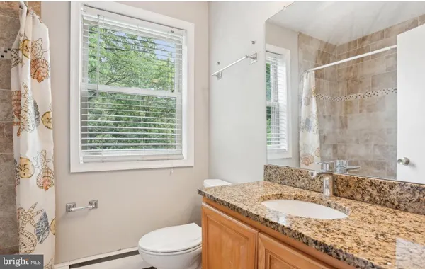 a bathroom with a granite countertop sink toilet and shower