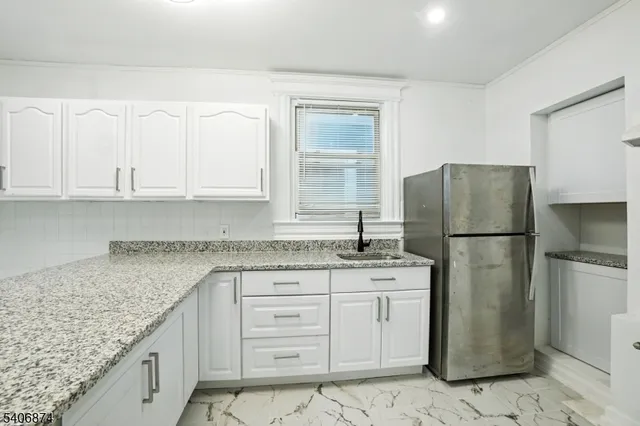 a kitchen with a granite countertop refrigerator sink and cabinets
