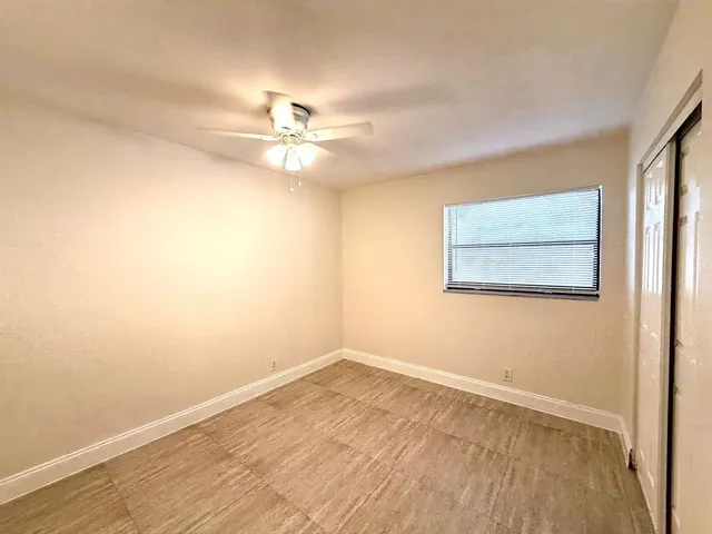 an empty room with wooden floor and ceiling fan