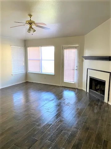 an empty room with wooden floor fireplace and windows