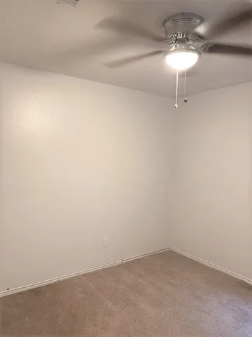 a view of an empty room with a chandelier fan