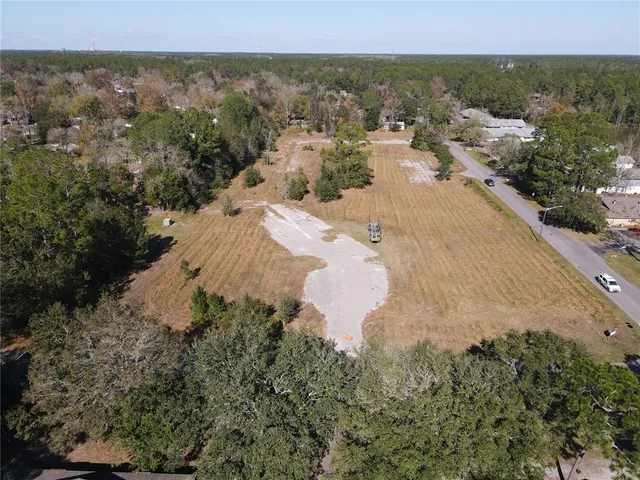 an aerial view of residential houses with outdoor space and trees