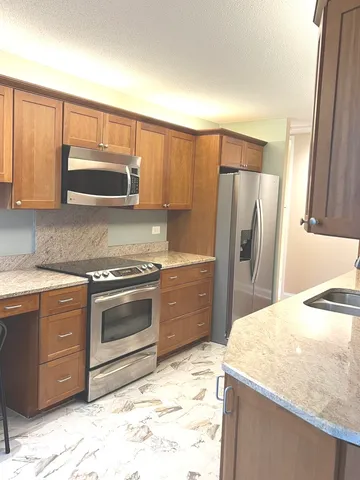 a kitchen with granite countertop a refrigerator and a stove top oven