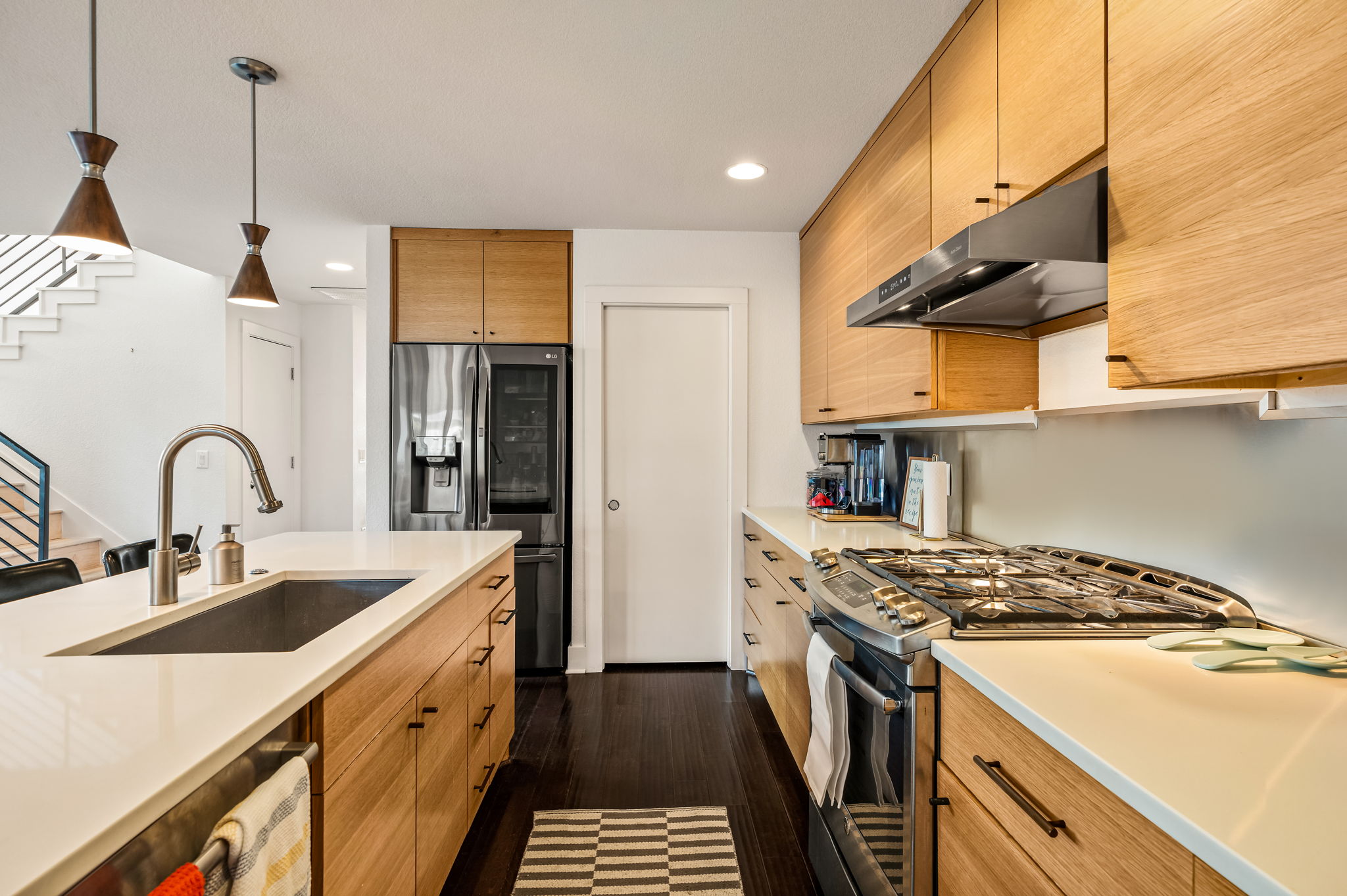 1124 Linden Street, Unit B Austin, TX 78702 - Photo 4 of 26 Kitchen featuring stainless steel appliances, pendant lighting, dark wood finished floors, light stone countertops, and wood finish cabinets