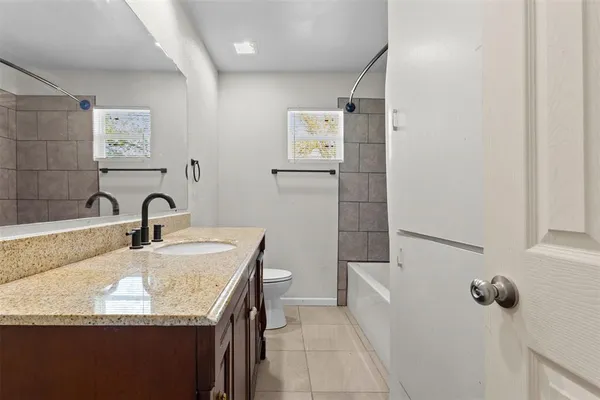 a bathroom with a granite countertop sink and a bathtub