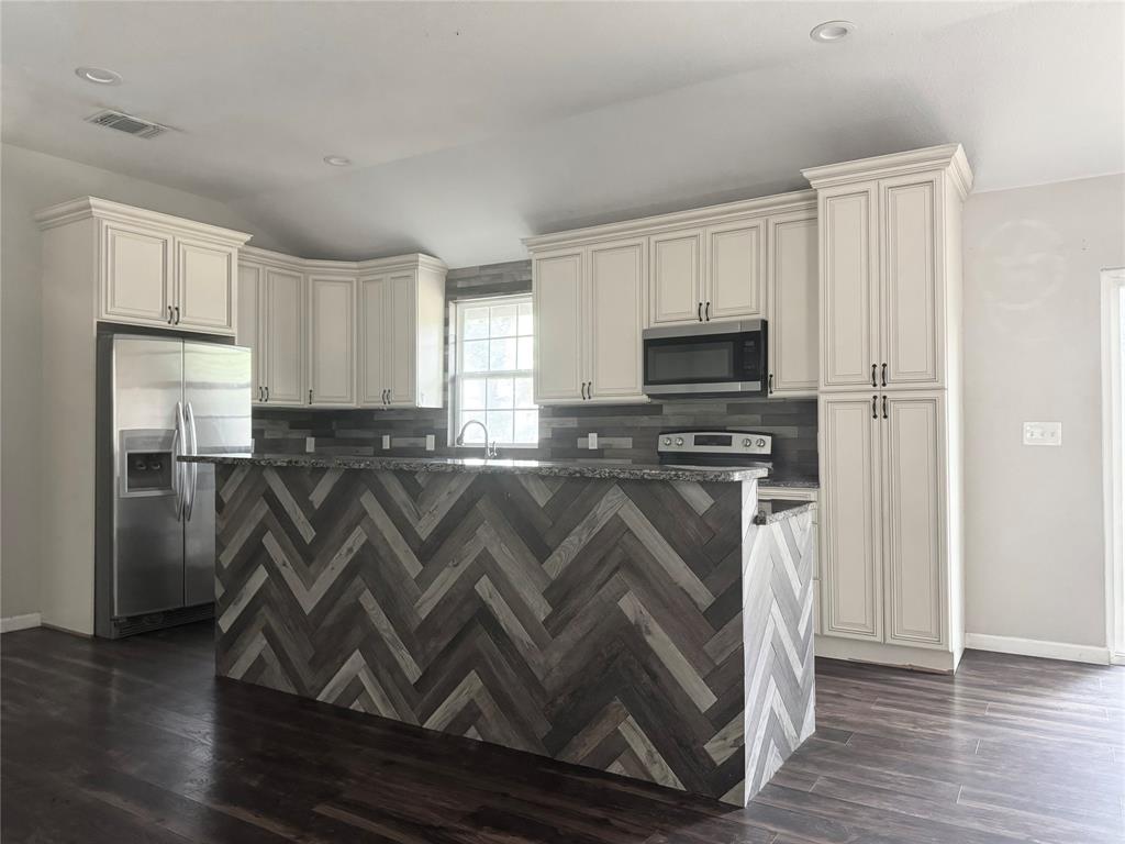 314 North Dubellette Street Weatherford, TX 76086 - Photo 27 of 30 a kitchen with granite countertop a refrigerator and a stove top oven