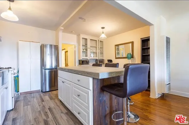 a kitchen with stainless steel appliances granite countertop a refrigerator a stove and a dining table with wooden floor