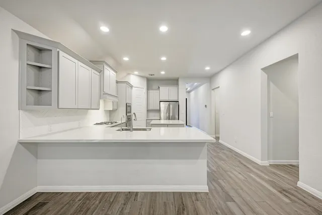 a kitchen with stainless steel appliances kitchen island granite countertop a stove a refrigerator and a sink