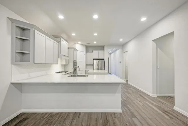 a kitchen with stainless steel appliances kitchen island granite countertop a stove a refrigerator and a sink