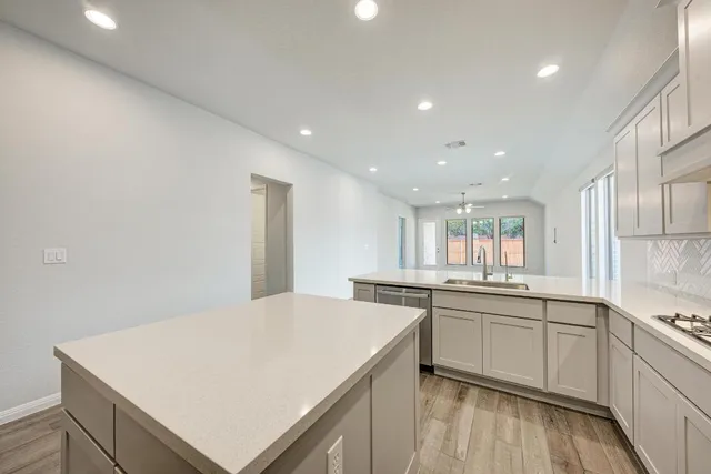 a kitchen with a sink a stove a refrigerator and white cabinets with wooden floor